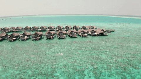 Drone aerial view of water bungalows in The Maldives. Luxury resort filmed from the air with a drone 