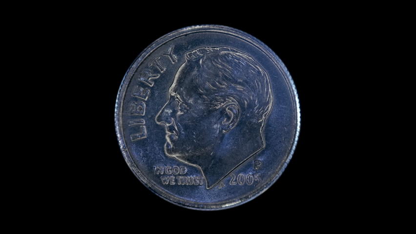 On a black background, one dime coin is glitters in the rays of light. Macro. Closeup