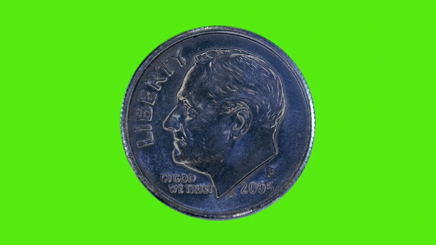 On a green chroma key background, one dime coin is glitters in the rays of light. Macro. Closeup