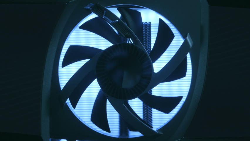 In the dark the cooling fan is spinning on the video card, light illuminates the cooler from the inside. Macro. Closeup. In work video adapter (graphics adapter, graphics card, graphics accelerator) Royalty-Free Stock Footage #1071194002