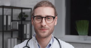 Portrait of Male Therapist Doctor talking to the Camera with Smile, Video call. Caucasian Medical with Eyeglasses energy holding Online Training. Wearing white Uniform with Stethoscope. Distant Work.