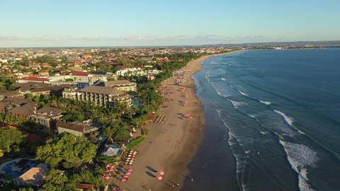 Dramatic aerial footage of the late afternoon of the famous Seminyak beach in Kuta, Bali, Indonesia. Shot with a backward and tilt down motion.  