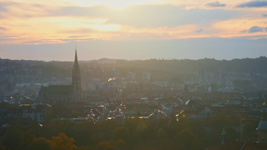 Cityscape of Graz with Church of the Sacred Heart of Jesus and historic buildings rooftops in Graz, Styria region, Austria, at sunrise