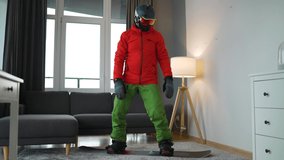 Fun video. Man dressed as a snowboarder depicts snowboarding on a carpet in a cozy room. Waiting for a snowy winter.