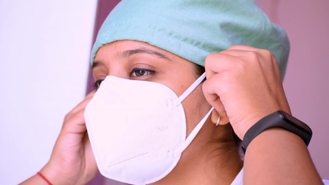 Portrait of confident young Indian female surgeon doctor in hospital wearing surgical mask and cap during corona virus pandemic in India