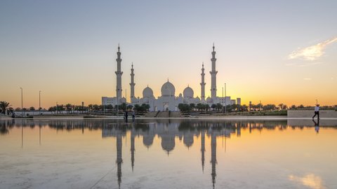 Sheikh Zayed Grand Mosque in Abu Dhabi day to night transition timelapse after sunset, UAE. Evening view from Wahat Al Karama with reflections on water