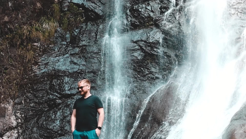 male tourist at the waterfall in the mountains