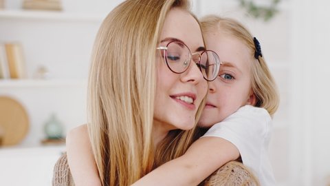 Portrait of happy young mother caucasian woman in glasses with daughter hugging at home talking smiling enjoying bonding. Little girl child preschool baby kid embrace hug beloved mom by neck cuddling