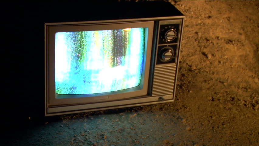 retro TV sitting on the dirt at night. 