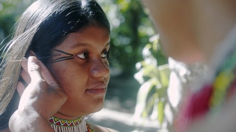 Young Brazilian girl indigenous Pataxó ethnicity doing face painting. 6K.