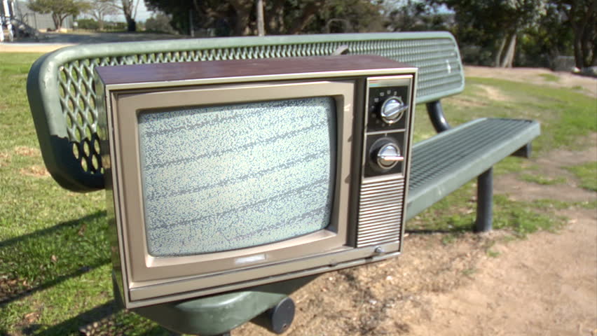 retro analogue TV sitting on a park bench.