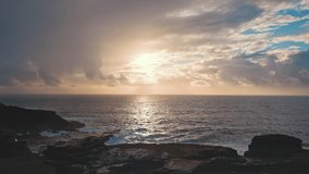 Dramatic sunrise over the ocean. Rocky coast of the island of Oahu Hawaii. A ray of the sun breaks through the clouds. Sunny path on the water.