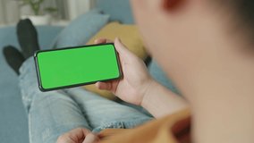 Male Using A Smartphone With Green Screen Display At Home Living Room While Lying On Sofa, Video In 4K
