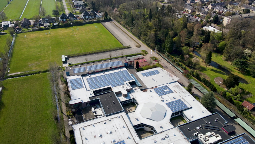 Aerial overview of large high school with solar panels on rooftop