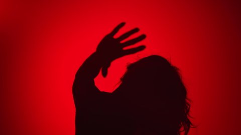 Female dancer with waving hair dancing raising hands playing enjoying freedom. Woman performing modern choreography isolated on red gradient darkness slow motion. Medium close up shot.