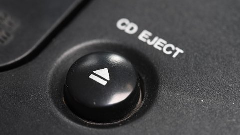 Close-up of a man's finger presses the mechanical button for ejecting a cd disc from a retro turntable