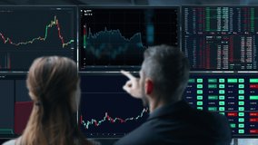 Colleagues traders are working with multiple computer screens full of charts and data analysis and stock broker trading online. Back view. Concept of bitcoin and stock market trading. - Powered by Shutterstock - Get 15% off with code: PIKWIZARD15