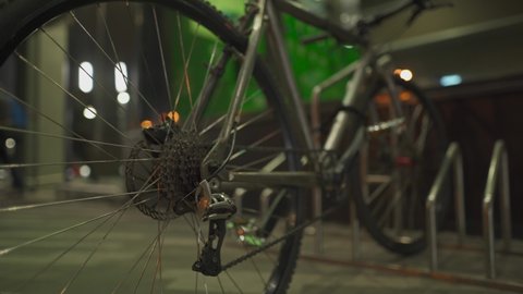 Unrecognizable man breaks anti-theft lock with master key, steals bicycle from parking lot near supermarket in evening. Theft of bicycles. Stolen bike. Male thief steals cycle at night from parking