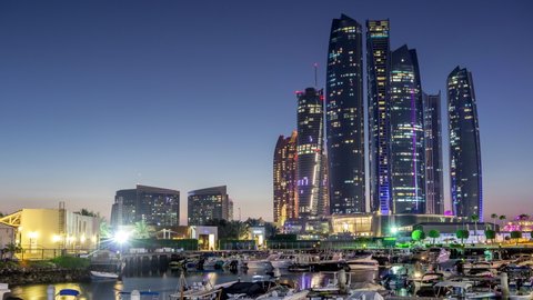 Al Bateen marina Abu Dhabi day to night timelapse after sunset with boats and illuminated modern skyscrapers on background