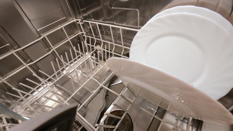 Rinsing plates in the dishwasher in standard mode. A powerful stream of water passes through the dishwasher basket. Close-up. 4k footage.