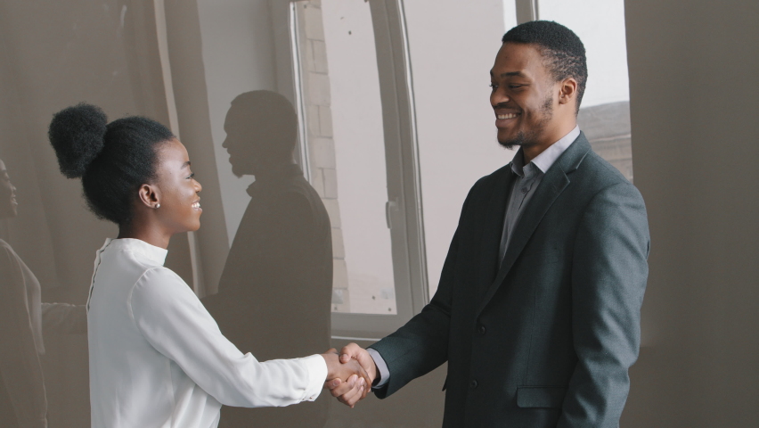 Happy young African American ethnicity businesswoman shaking hands with male employer after project negotiations, successful business meeting, making deal in office. Intern get positive feedback. Royalty-Free Stock Footage #1071262873