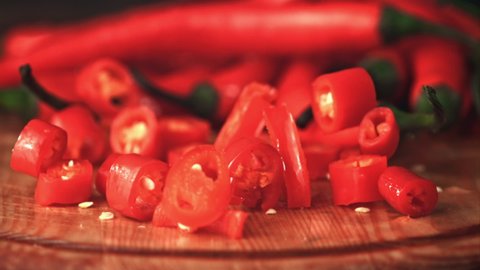 Super slow motion pieces of chilli pepper fall on the cutting board. On a wooden background. Filmed on a high-speed camera at 1000 fps. High quality FullHD footage