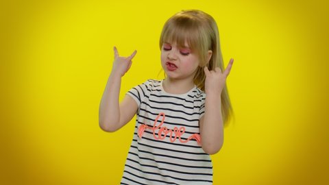 Overjoyed delighted funny playful blonde kid child showing rock n roll gesture by hands, cool sign shouting yeah with crazy expression, dancing emotionally rejoicing in success. Teenager children girl