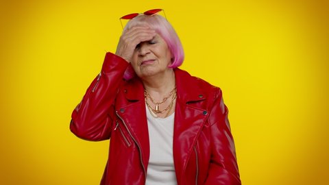 Upset stylish elderly granny woman in jacket wish, waiting for good luck, loses becoming surprised sudden lottery results, bad fortune loss. Senior rocker old grandmother isolated on yellow background