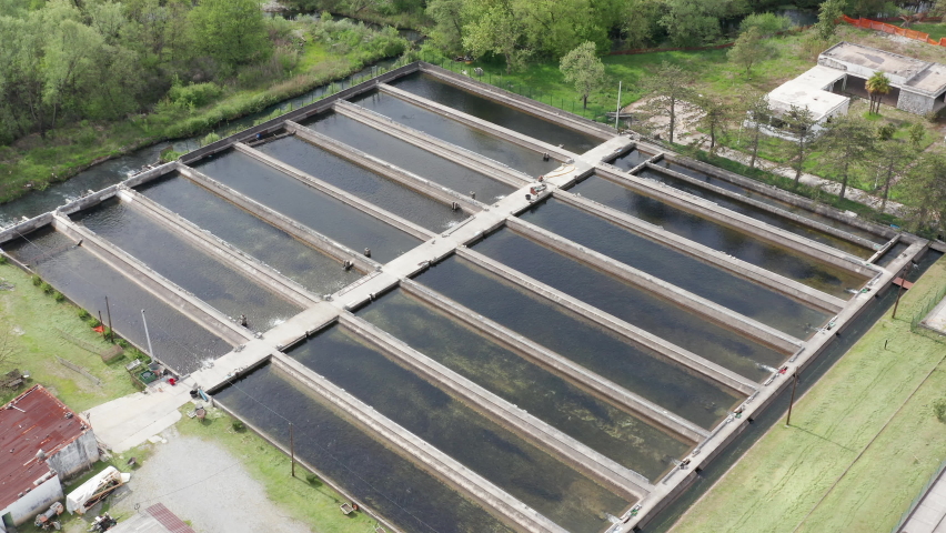 Fish ponds in an aquaculture farm - farming enclosures with fresh water where fish is raised commercially for food. Aerial view of the tanks in agricultural industrial plant.