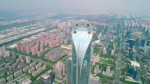 Suzhou, China - September 04, 2020: Aerial orbital cityscape skyscaper under construction with reflections on the glass windows and roads with moving cars in a business district of Suzhou, China. 