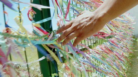 Closeup of colorful ribbons in Bahia, Brazil. Man hand making an request with Brazilian ribbons. Faith. 6K.
