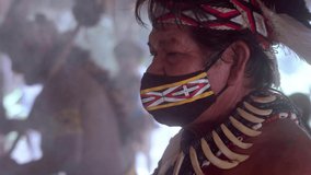 Shaman of the Pataxó tribe in spiritual event. Elderly Indian man wearing feather headdress and face mask due to the covid-19 pandemic. Brazilian Indian. 6K. - Powered by Shutterstock - Get 15% off with code: PIKWIZARD15