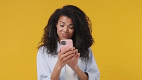 Dreamful pensive african woman curly hair 20s years old wears blue white t shirt hold using mobile cell phone typing browsing chatting send sms isolated on yellow color wall background studio portrait - Powered by Shutterstock - Get 15% off with code: PIKWIZARD15
