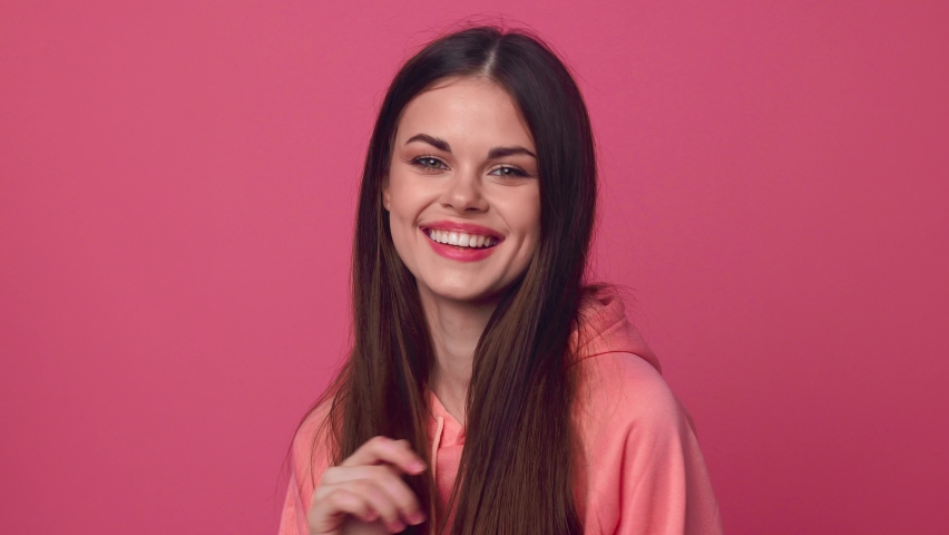Woman on a pink background posing and smiling beautifully while looking at the camera | Shutterstock HD Video #1071270661