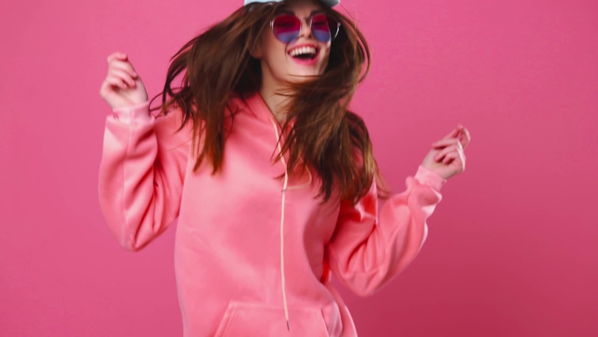 Happy woman with a beautiful smile dancing and jumping on a pink background, positive emotions | Shutterstock HD Video #1071270664
