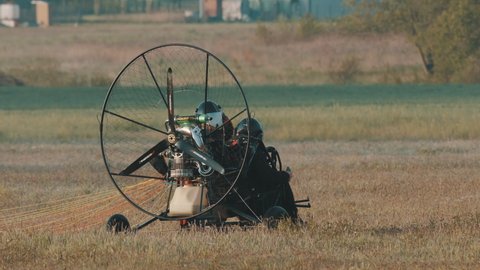 Warsaw, Poland 05.23.2020 Two persons at paramotor trike, necessary preparing for flight. Tandem motor powered paragliding at twilight. 