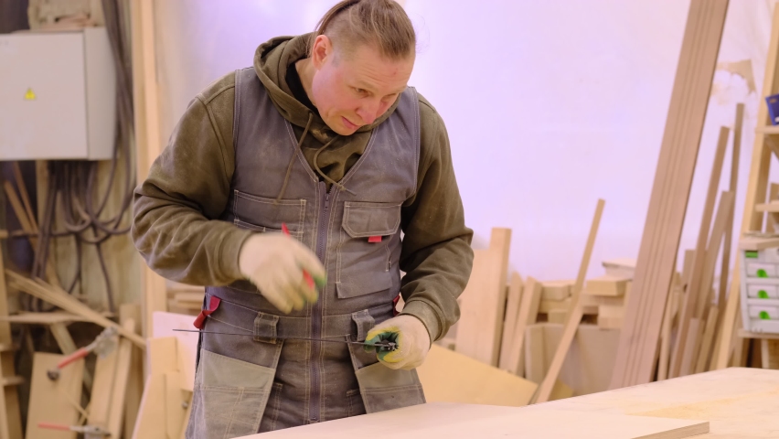 Close up. Carpenter holding a measure tape on the work bench. Woodwork and furniture making concept. Carpenter in the workshop marks out and assembles parts of the furniture cabinet
