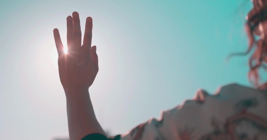 Waving hand to glare of sun flare in afternoon time, urban street. Woman's hand on balcony, sunbeams an gesture. | Shutterstock HD Video #1071283468