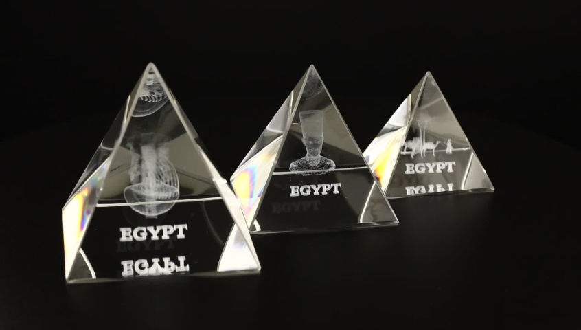 Three glass pyramid with the inscription Egypt rotates on a black background. Close-up video of the decor.