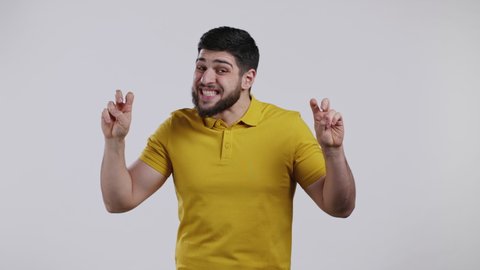 Handsome man showing with hands and two fingers air quotes gesture, bend fingers isolated on white background. Guy in yellow wear. Not funny, irony and sarcasm concept.