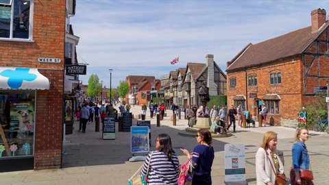 William Shakespeare's Statue in Stratford-upon-Avon. People walk on a sunny day and buy ice cream. Time lapse shot in center of the old town. April 24, UK 2021