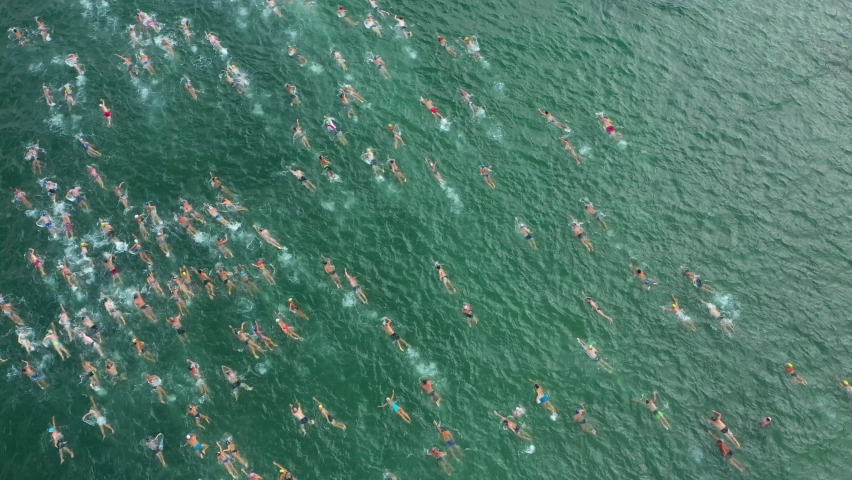 Aerial Drone Shot 4K of Triathlon Swimming Race. Ironman Competition. Traditional swimming marathon in Varna, Bulgaria. A huge group of people invades the water. Start swimming in the sea or ocean. Royalty-Free Stock Footage #1071288547