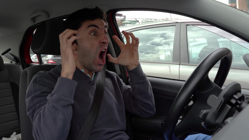 Furious man gesticulates with hands and horns driving on traffic jam. Crazy driver yelling from car desperately. Stress, traffic rush hour, anxious, madness, rudeness concepts | Shutterstock HD Video #1071288718