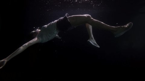 motionless and breathless female body is floating underwater, slow motion shot of sunken woman