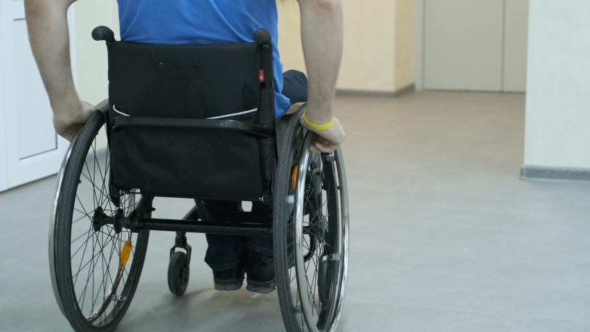 A man in a wheelchair enters the elevator. A person with a disability rides an elevator.