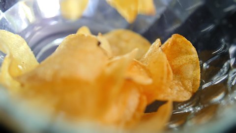 Slow motion macro shot of chips falling down into glass bowl