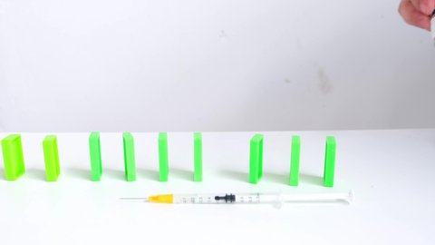 close-up medical syringe with vaccine stop dominoes continuous toppled or risk with copy space, concept to stop vaccination of population from spreading coronavirus, stop covid-19