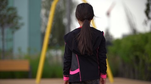 little girl playing on the playground. Happy child climbing up on playground net, riding a swing and bungee, active lifestyle