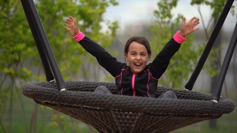 little girl playing on the playground. Happy child climbing up on playground net, riding a swing and bungee, active lifestyle
