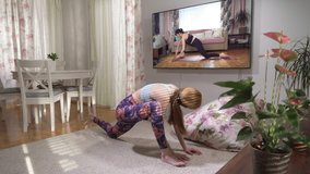 Young beautiful fit woman following yoga online video tutorial in her living room dining quarantine restrictions. Yoga, pilates, working out exercising